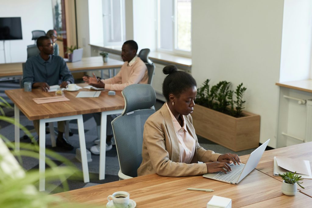 Diverse group of professionals collaborating in a modern office setting with laptops and discussions.
